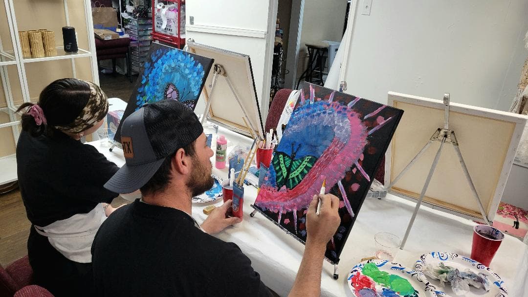 Two workshop participants at easels painting butterfly compositions.